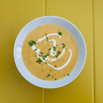 A bowl with potato soup, decorated with cream and parsely